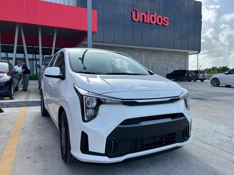 White Kia hatchback ready for pick-up in a car park in Punta Cana